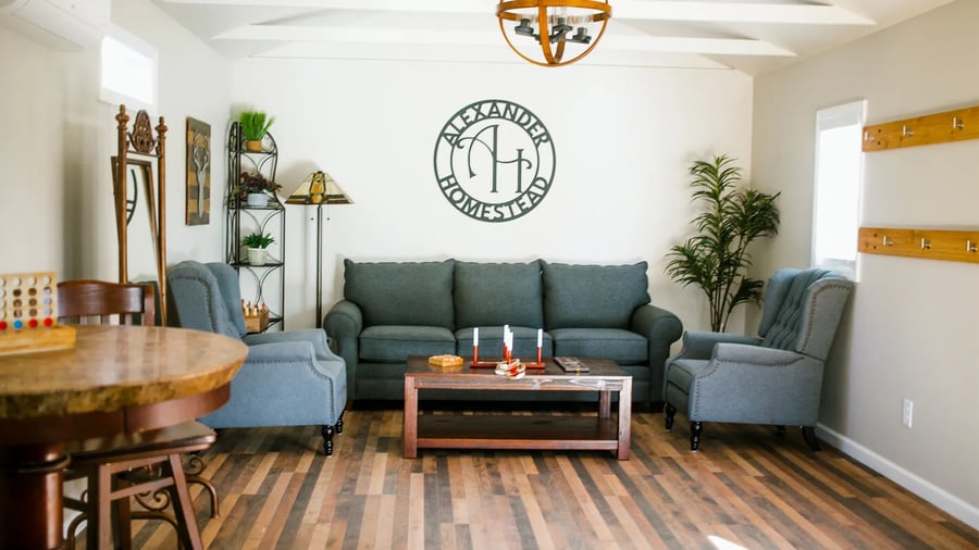 Cozy lounge area with blue furniture and Alexander Homestead logo at the Charlotte wedding and event venue featuring rustic wood