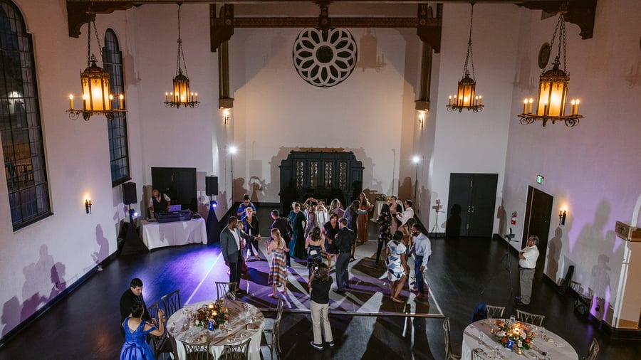 Expansive chapel reception with stained glass, wrought iron chandeliers, and dance floor at Fillmore Chapel by Wedgewood Events