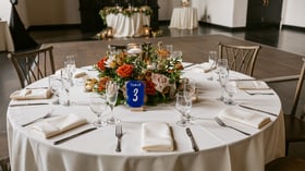 Indoor reception with vibrant orange and pink floral centerpieces at Fillmore Chapel by Wedgewood Events