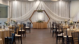 Event reception table setting with crystal glassware, champagne, white floral centerpieces, and cozy fireplace backdrop