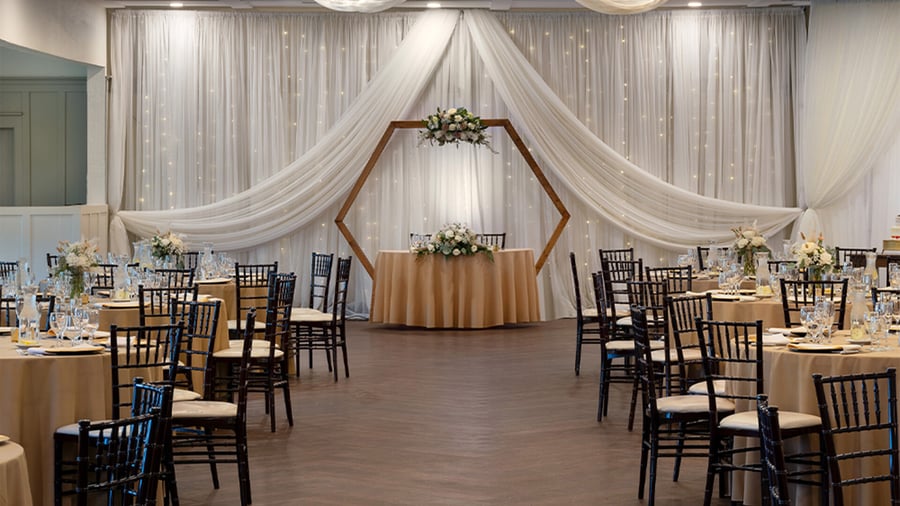 Event reception table setting with crystal glassware, champagne, white floral centerpieces, and cozy fireplace backdrop
